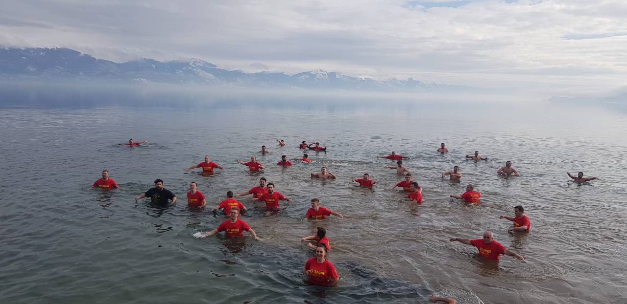 Zwemmers in het koude water van het Prespameer op zoek naar het in het water gegooide kruis